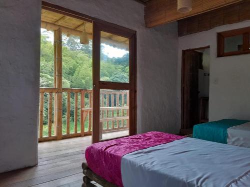 a bedroom with a bed and a view of a balcony at Cabañas rurales Arabi in Pereira