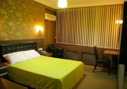 Habitación de hotel con cama verde y escritorio. en Hopa Heyamo Hotel, en Hopa
