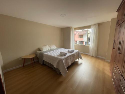 een slaapkamer met een bed, een tafel en een raam bij Casa Terminal Terrestre in Loja