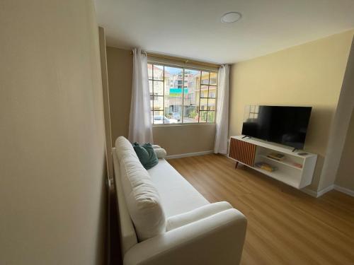 een woonkamer met een witte bank en een televisie bij Casa Terminal Terrestre in Loja
