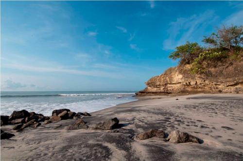 a sandy beach with rocks and the ocean at Villa Vita Oceanfront Mansion in Santa Teresita