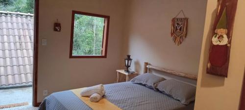 a bedroom with a bed and a window at Chalé Cogumelo in Visconde De Maua