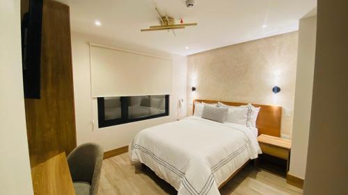 a bedroom with a white bed and a television at Saya Hotel & Suites in Cuenca