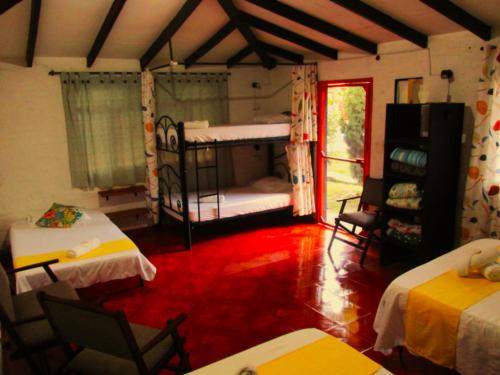 Melao Hostel Campestre y Vivero في بالميرا: غرفة بها سريرين بطابقين وطاولات وكراسي