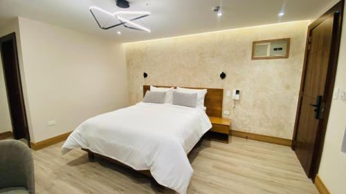a bedroom with a white bed and a ceiling fan at Saya Hotel & Suites in Cuenca