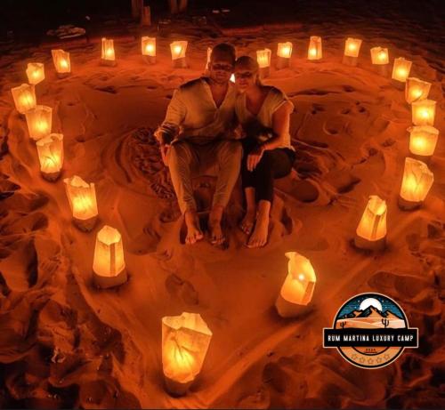 a man and woman sitting in a circle of candles at RUM MARTINA lUXURY CAMP in Wadi Rum