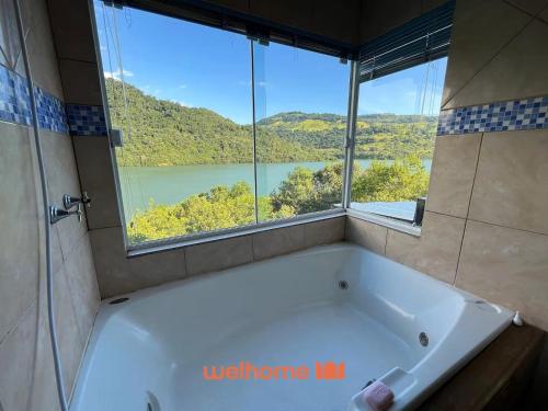 een badkuip in een badkamer met een groot raam bij Casa em Chapeco com Piscina Privativa e Vista Lago in Nonoai