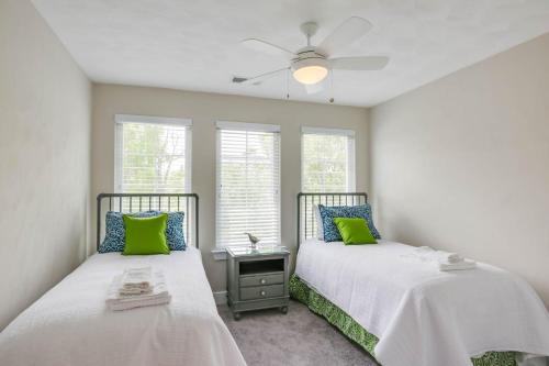 two beds with green pillows in a room with windows at 519 The Great Neck House in Virginia Beach