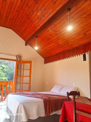 a bedroom with a bed and a wooden ceiling at Chalé Sophia in Camanducaia