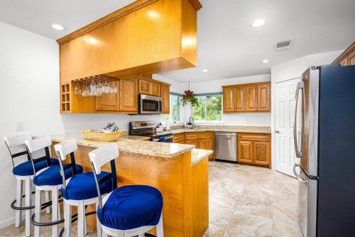 a kitchen with wooden cabinets and blue bar stools at Riverfront Private Deck Family Games Wurstfest Fun in Seguin