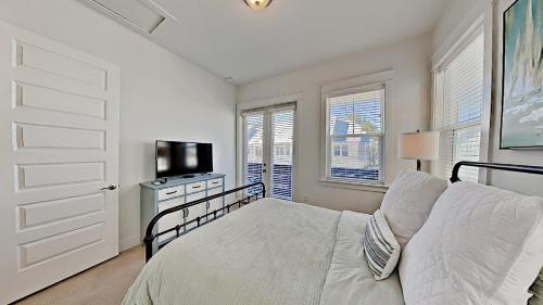 a bedroom with a bed and a tv and windows at Settle By The Sea in Inlet Beach