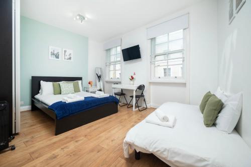 a bedroom with two beds and a desk in it at Soho Central Apartments in London