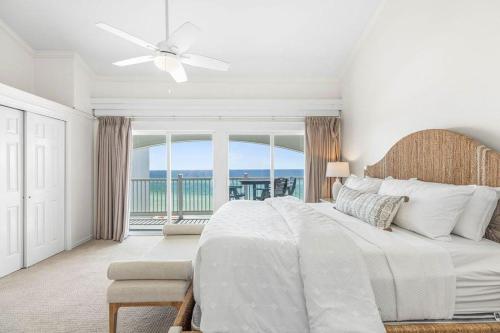 a white bedroom with a bed and a balcony at Blue Tide 6B in Inlet Beach