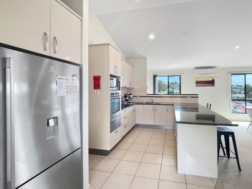 a kitchen with white cabinets and a stainless steel refrigerator at Beachside Retreat with Garage Parking in Surf Beach