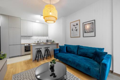 a living room with a blue couch and a kitchen at Premier Nova Residence in Novi Sad