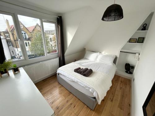 a small bedroom with a bed and two windows at Cosy 3 Bedroom Flat, Hackney Central in London