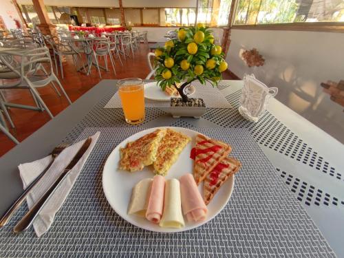 a plate of food with two slices of pizza and orange juice at Hotel Margarita Dynasty in Porlamar