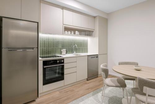 a kitchen with white cabinets and a table with chairs at Quest Bairnsdale in Bairnsdale