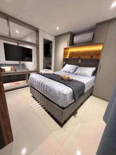 a bedroom with a large bed and a tv at Studio 124 luxuoso, novo, bem equipado com ar condicionado e cozinha completa - Centro Mogi in Mogi das Cruzes
