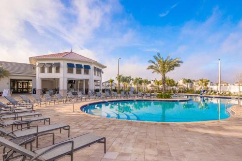 a swimming pool with chairs and a building at 4964RS TOWNHOUSE 4 BEDROOMS & 3 BATHROOMS + POOL in Kissimmee