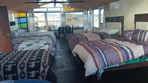 three beds in a room with a view of the water at cabañas del inka in Puno