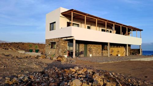 un edificio en la playa con rocas delante en Kasa surf, en Porto Novo