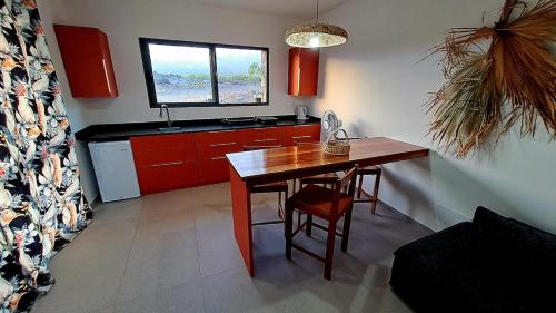 una cocina con mesa de madera y una cocina con armarios rojos. en Kasa surf, en Porto Novo