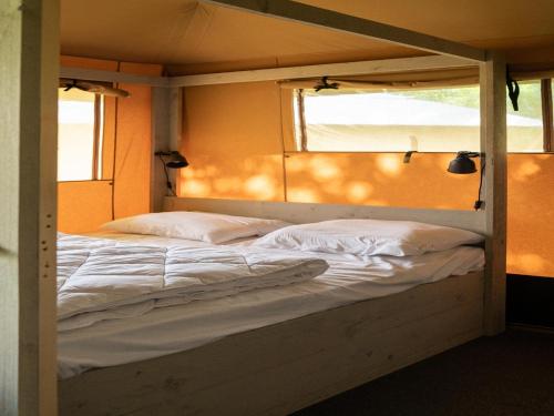 a large bed with white sheets and pillows in a room at Luxury Family Tent with Play Area in Balkbrug