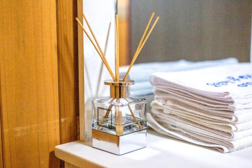 a glass vase with sticks in it on a table with towels at Suncheonman Muhan Dojan Pension in Suncheon