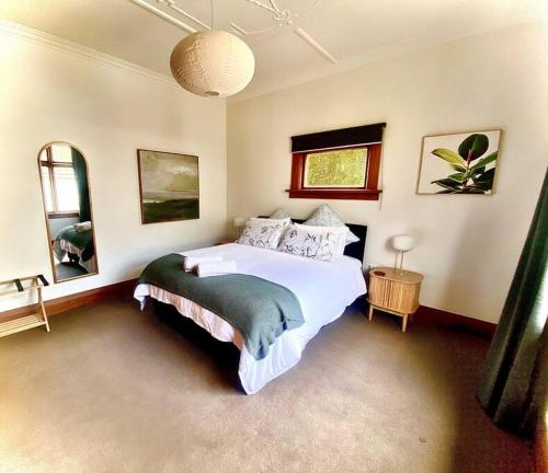 a bedroom with a large white bed in it at Rose Cottage - Charming 2 Bedroom Home in Dunedin
