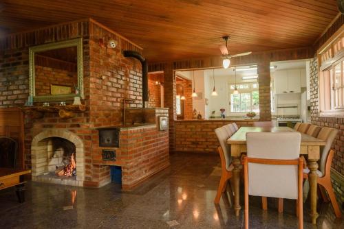 eine Küche mit einem gemauerten Kamin und einem Tisch mit Stühlen in der Unterkunft Maison Valle in Taquara