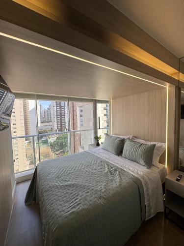 een slaapkamer met een groot bed met een groot raam bij Apartamento Novo no Melhor Bairro de Londrina in Londrina