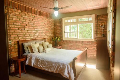 a bedroom with a bed in a brick wall at Maison Valle in Taquara