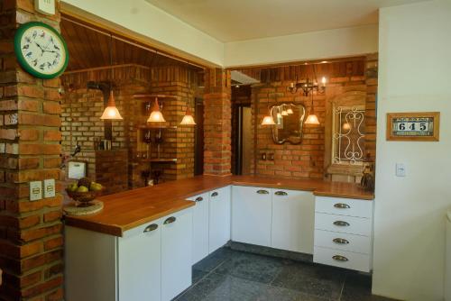 a kitchen with white cabinets and a clock on a brick wall at Maison Valle in Taquara