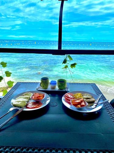dos platos de comida en una mesa con el océano en el fondo en Mi Cabañita Guest House, en Playa Blanca