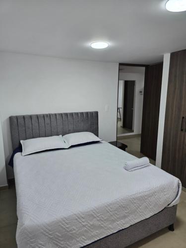 ein Schlafzimmer mit einem großen Bett mit weißer Bettwäsche in der Unterkunft Posada Los Geranios in Duitama