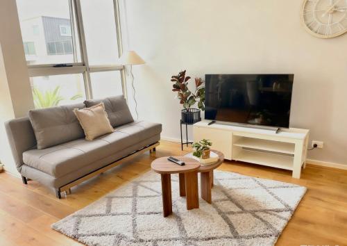 a living room with a couch and a flat screen tv at Modern Two-Level Apartment in the Heart of Epping in Epping