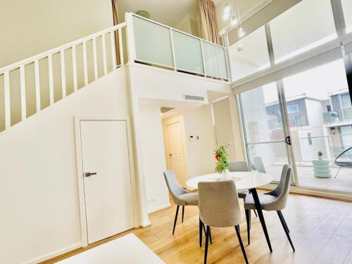 a dining room with a white table and chairs at Modern Two-Level Apartment in the Heart of Epping in Epping
