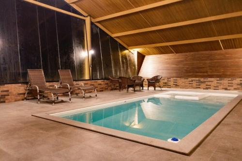 a pool in a house with chairs and a table at Vistas de Mantiqueira in Bom Jardim da Serra