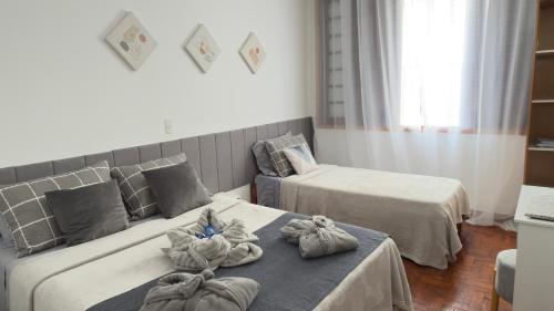 a hotel room with two beds with towels on them at Apartamento Pé na Praça Conforto e Charme no Coração de Serra Neg in Serra Negra