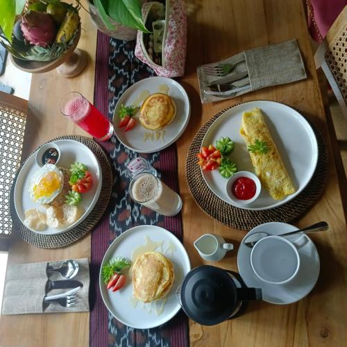 Una mesa con platos de comida para el desayuno. en Shaka bali villa, en Ubud