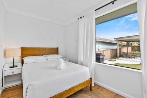 Un dormitorio con una cama y una ventana grande en Harbour Mist Hideaway - Where Coast Meets Calm, en Ulladulla