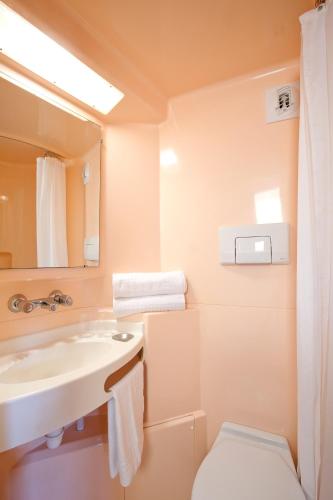 une salle de bain avec un lavabo, des toilettes et un miroir dans l'établissement Hotel Cerise Nancy, à Nancy