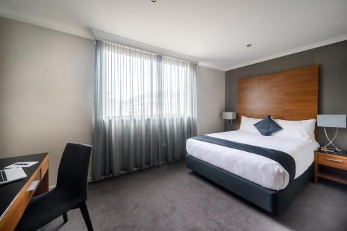 a hotel room with a large bed and a desk at Crest on Barkly Hotel in Melbourne