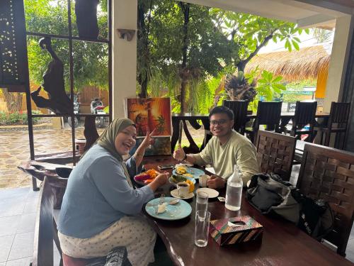 a man and a woman sitting at a table eating food at Sasak Garden Resort in Senggigi 