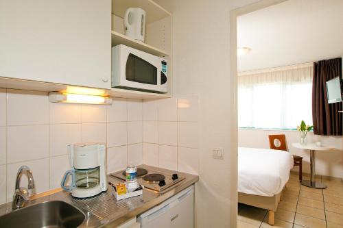 a kitchen with a sink and a room with a bed at Séjours & Affaires Serris Rive Gauche in Serris