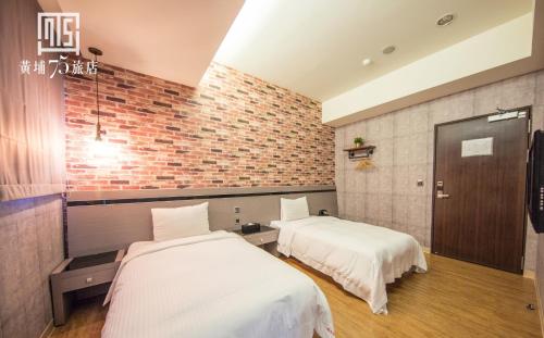 Dos camas en una habitación con una pared de ladrillo. en Military 75 Hotel, en Taichung