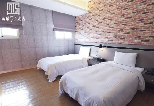 Dos camas en una habitación con una pared de ladrillo. en Military 75 Hotel, en Taichung