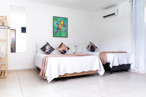 two beds in a room with white walls at Tucanos Buzios in Búzios