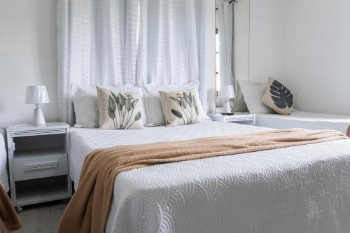 a bedroom with two beds with white sheets and pillows at Tucanos Buzios in Búzios